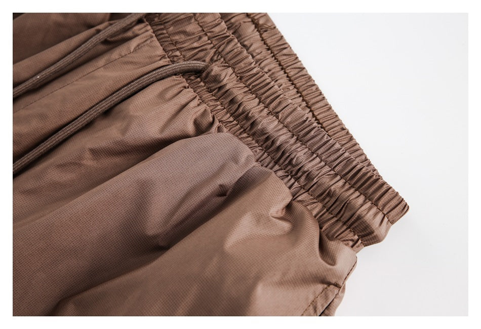 Close-up of brown shorts showing an elastic waistband and adjustable drawcords.