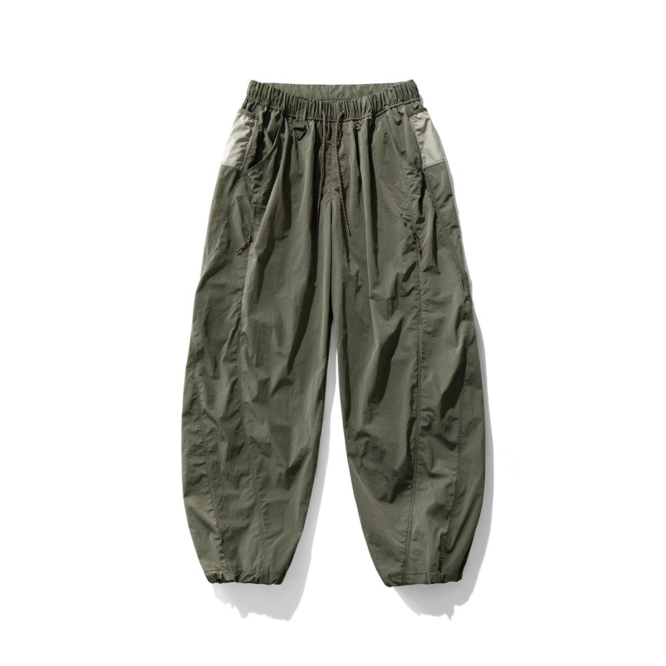 Army green wide-leg pants with drawstring waist, zip side pockets and light green side panels, flat lay