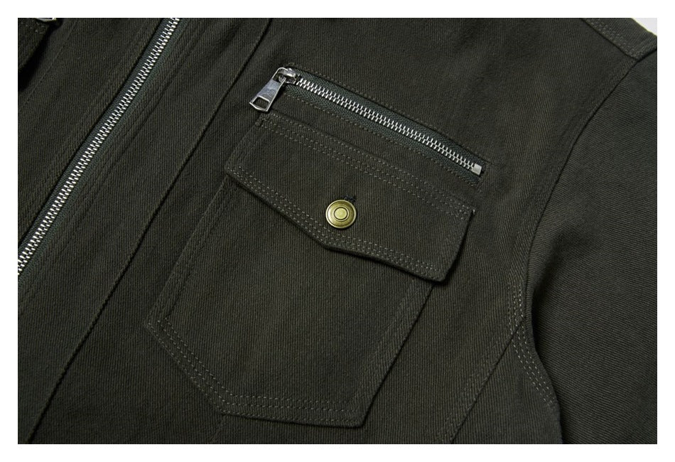 Close-up of a dark olive jacket pocket with a flap, brass-tone snap, and horizontal zipper.