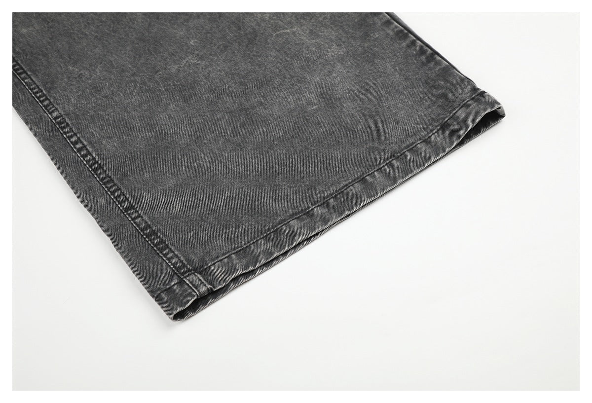 Close-up of the wide leg opening and stitched hem on charcoal-gray jeans.