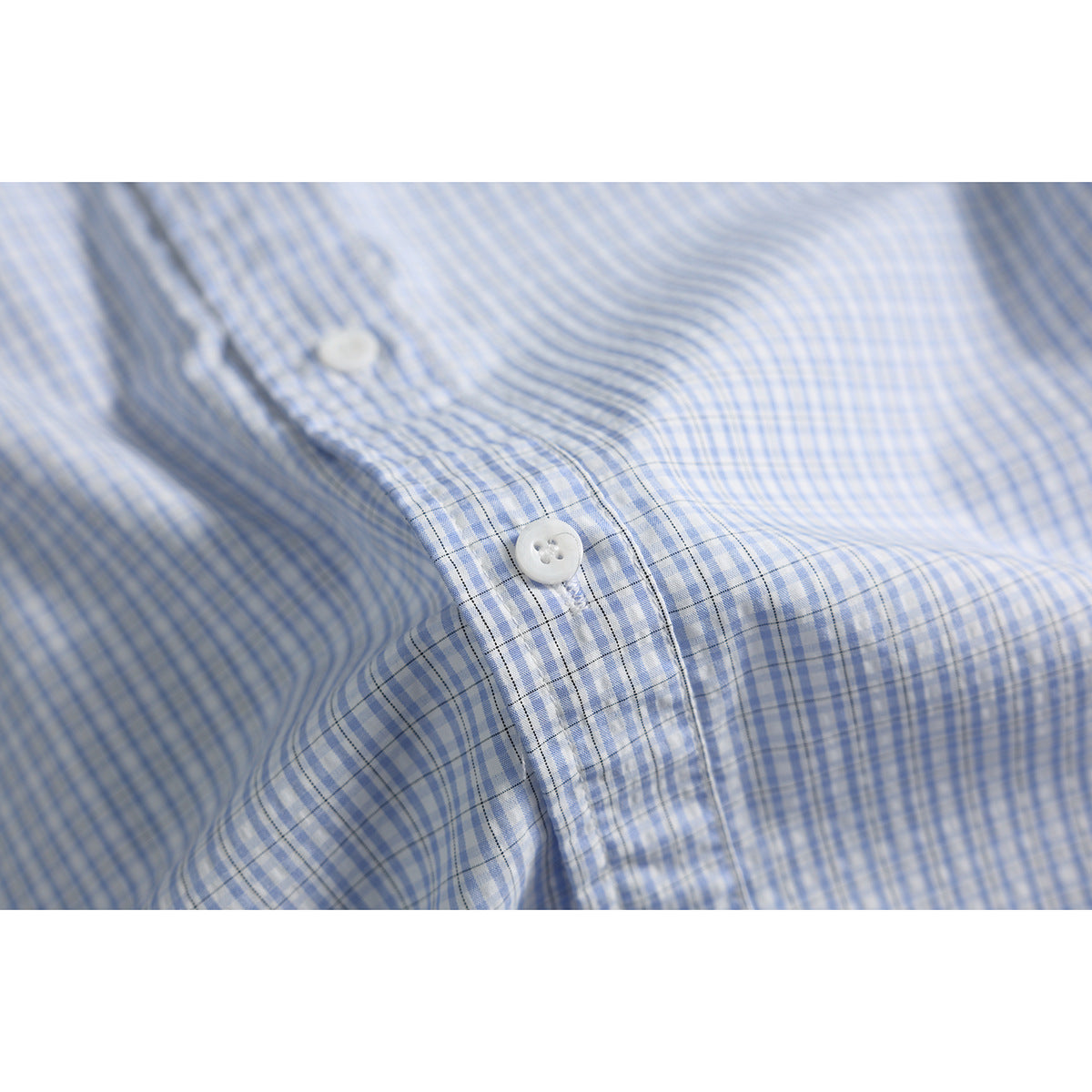 Close-up of a white button on the sleeve placket of a blue-and-white checked shirt.