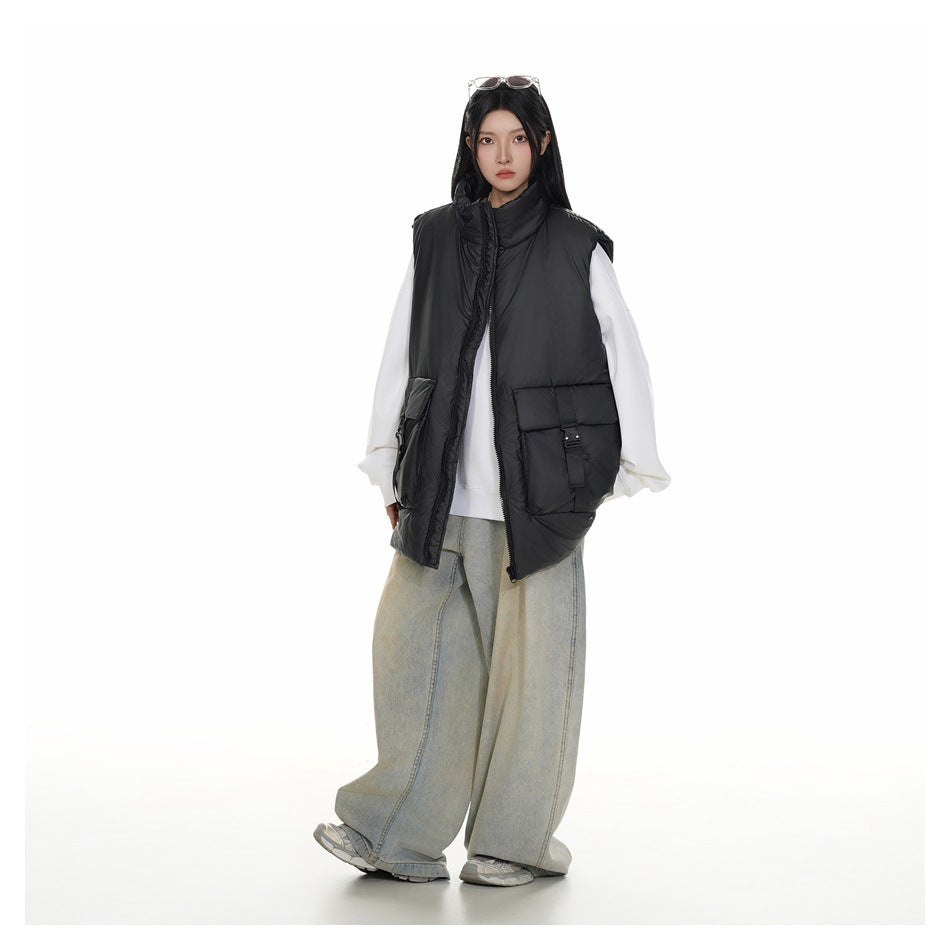 Full-length model wearing an open black padded vest with large flap pockets over a white sweatshirt and loose light-wash