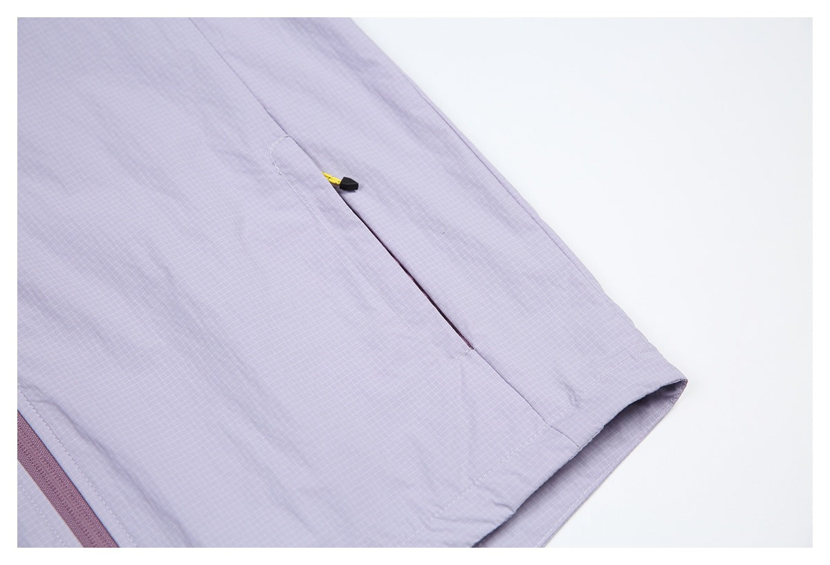 Lavender grid-patterned garment detail showing a narrow pocket with a yellow-and-black zipper pull and a finished hem.