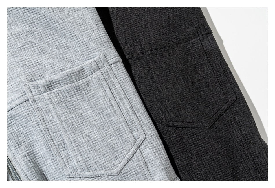 Close-up of patch pockets on light gray and black textured garments.