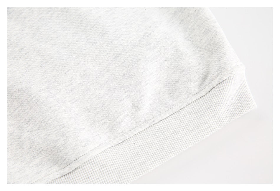 Close-up of light heather gray knit fabric meeting a wide ribbed band along a garment edge.