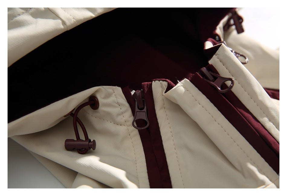 Close-up of the jacket's cream hood, burgundy lining, zipper pulls and drawcord toggle.