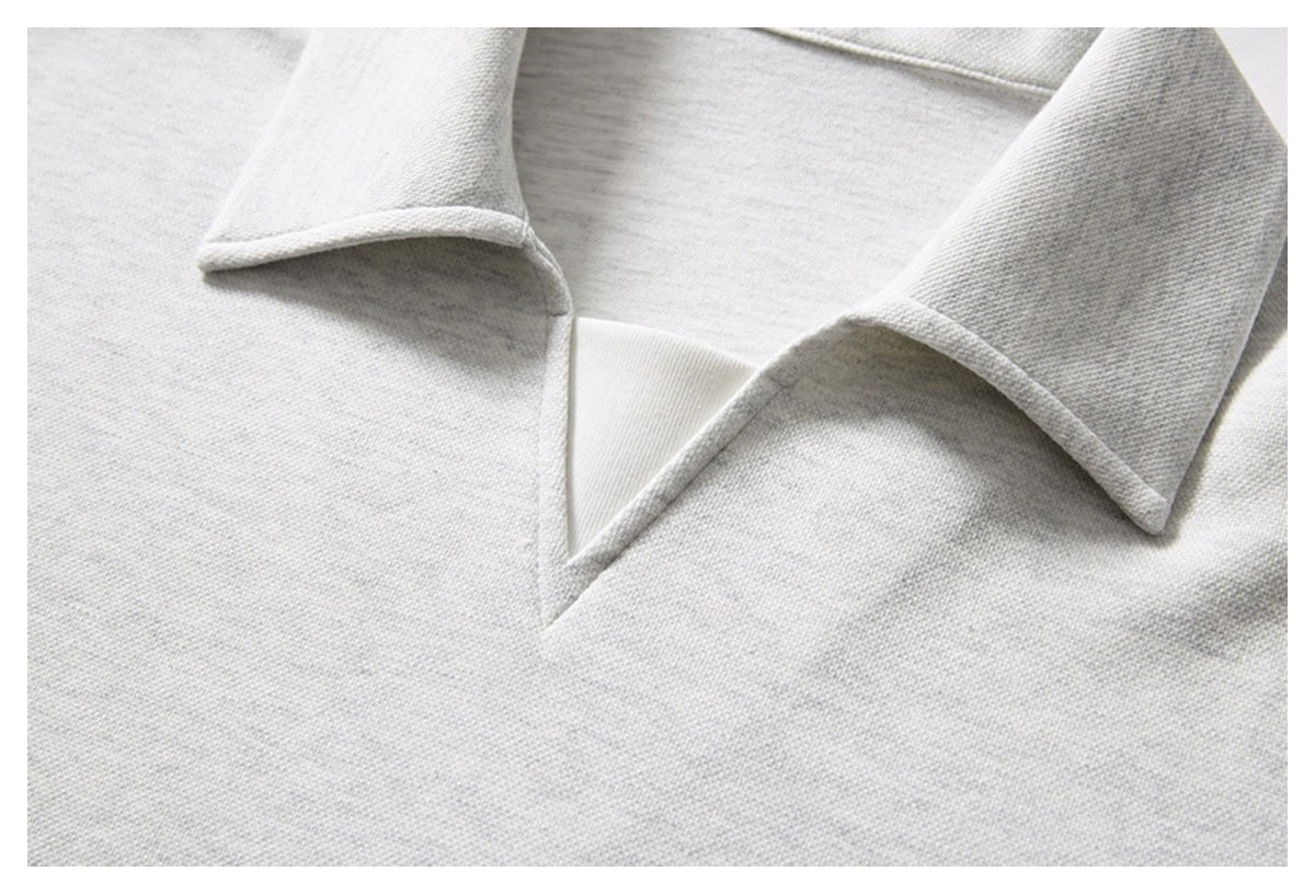 Close-up of the light gray knit polo shirt's folded collar and open neckline.