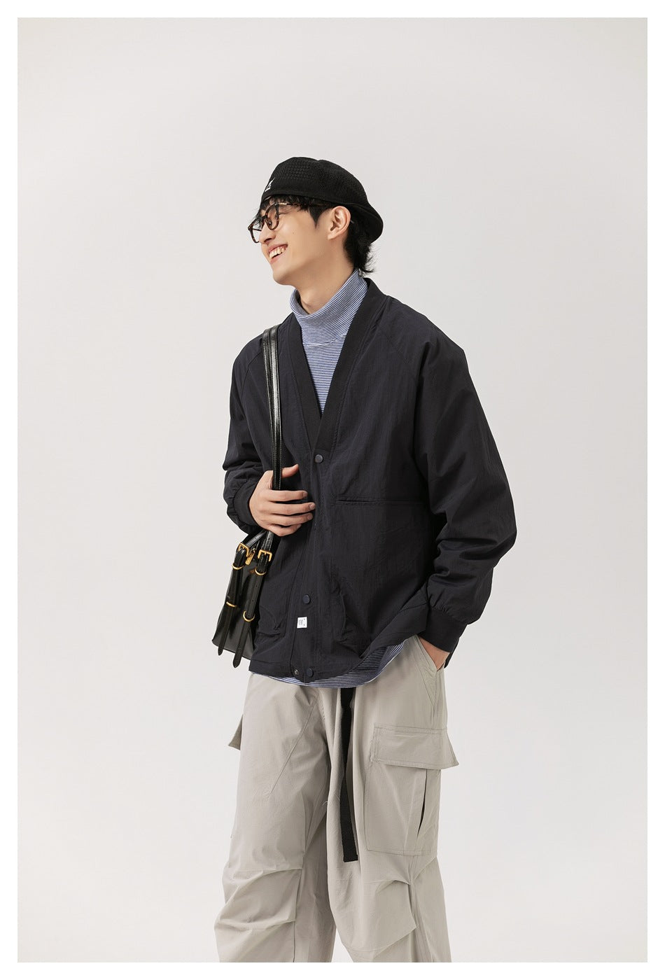 Model in a black cardigan jacket and striped top, shown from the side with light gray cargo pants.