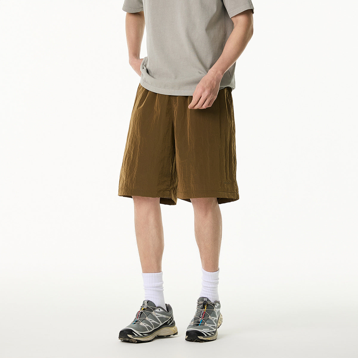 Cropped model wearing brown drawstring shorts with side pockets and a taupe T-shirt, shown from the front.