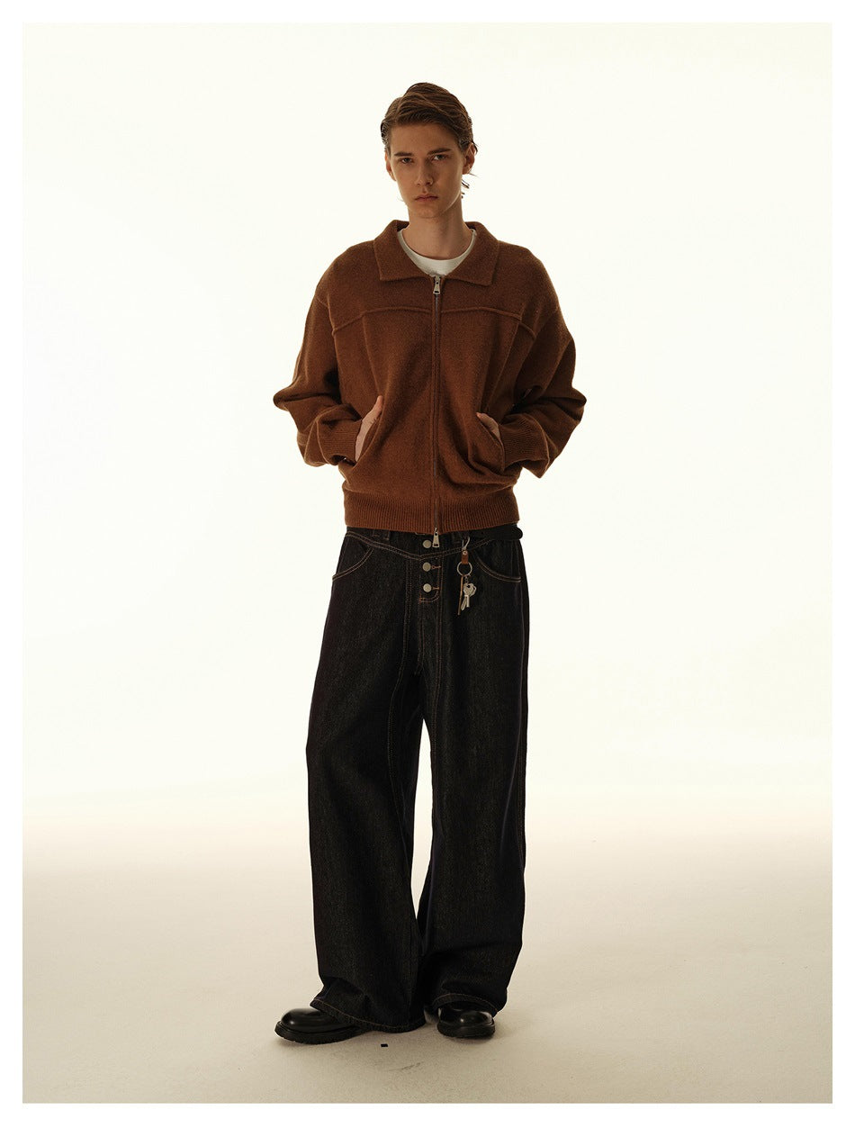Model wearing dark wide-leg button-fly jeans with a brown zip-up knit jacket and black leather shoes