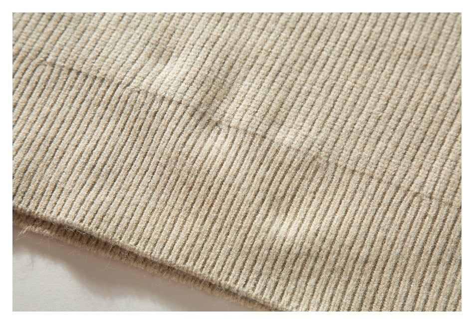 Close-up of the beige sweater's ribbed knit fabric and finished edge.