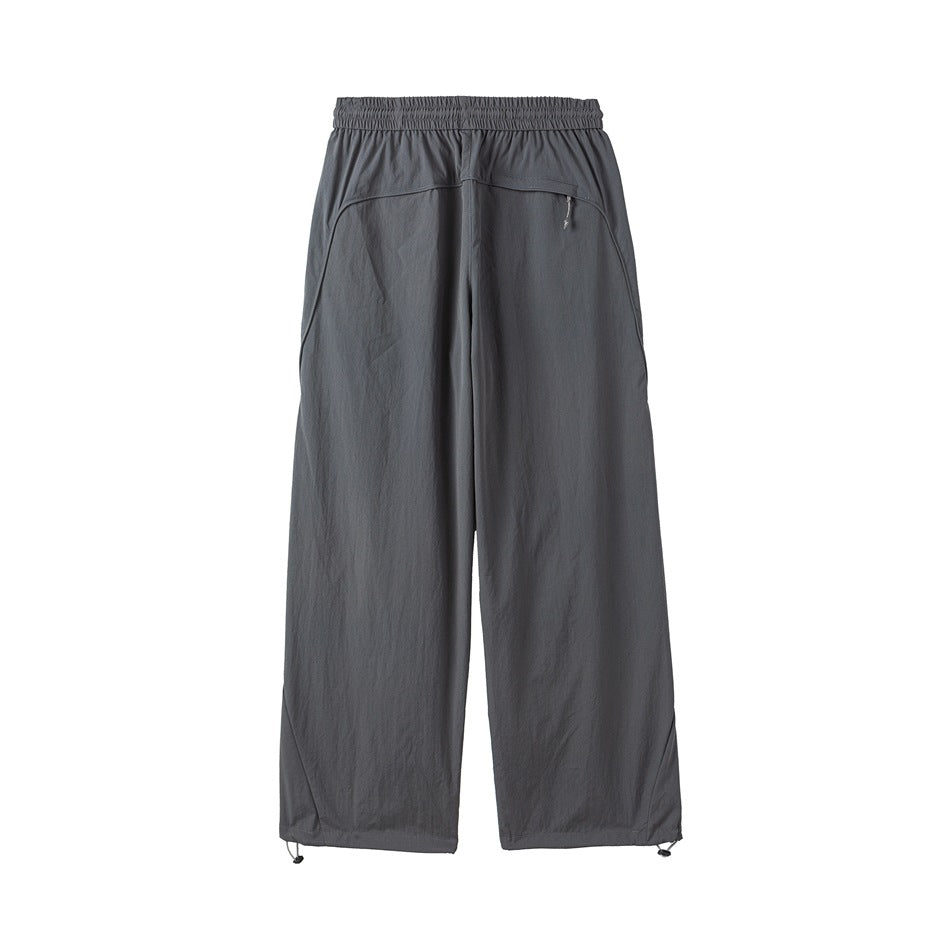 Back view of gray wide-leg trousers with an elastic waistband, curved zip pocket, and adjustable hems.