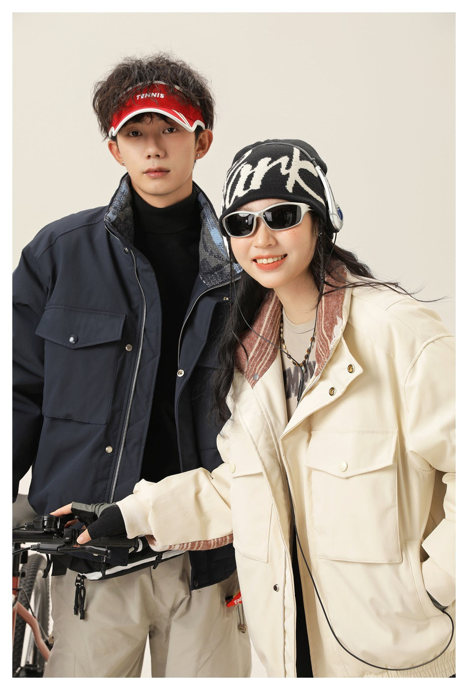 Two models in close-up wearing navy and cream utility jackets with flap pockets and patterned lining.