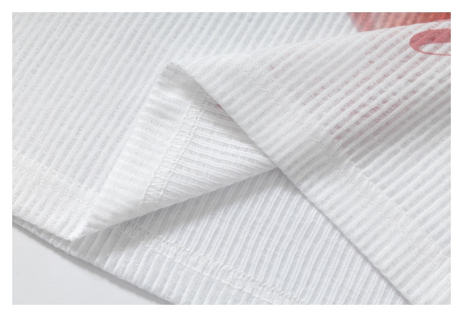 Close-up of white ribbed garment fabric folded to reveal stitching and a glimpse of pink print.