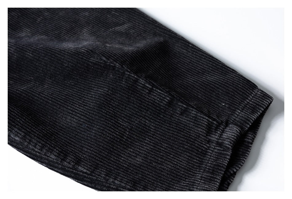 Close-up of black ribbed corduroy trousers showing a stitched edge and seam.