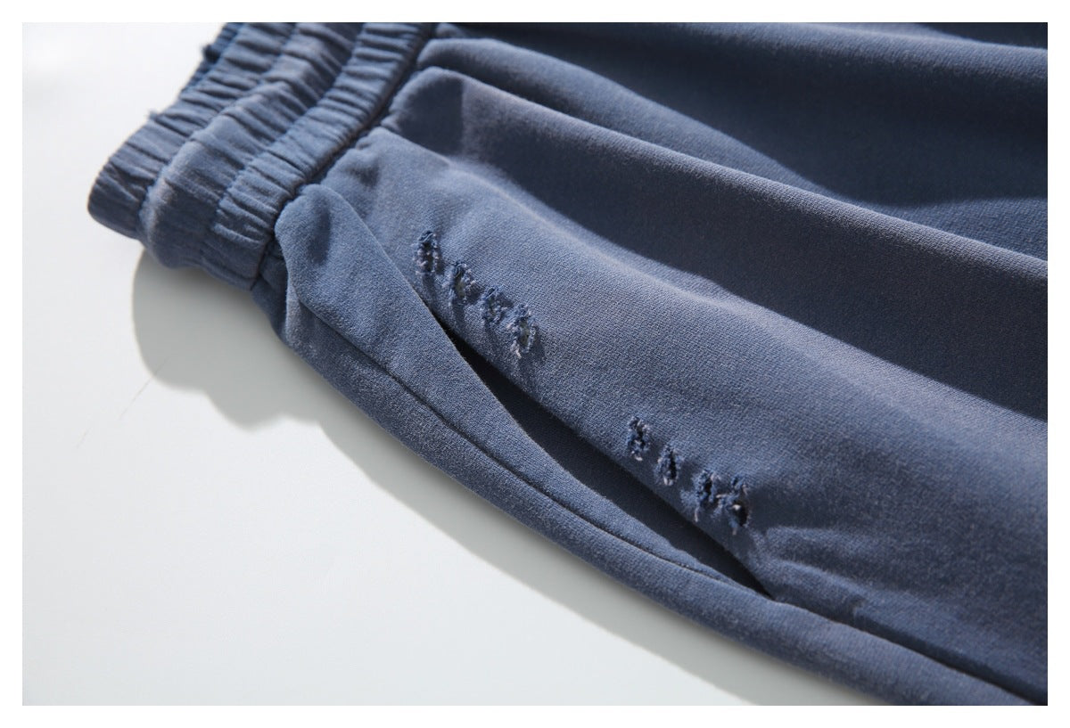 Close-up of slate-blue pants with small distressed details along a seam.