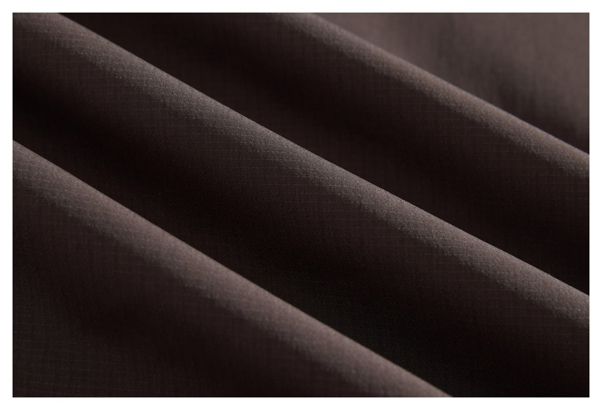 Close-up of dark brown fabric draped in soft folds, showing a subtle fine grid texture.