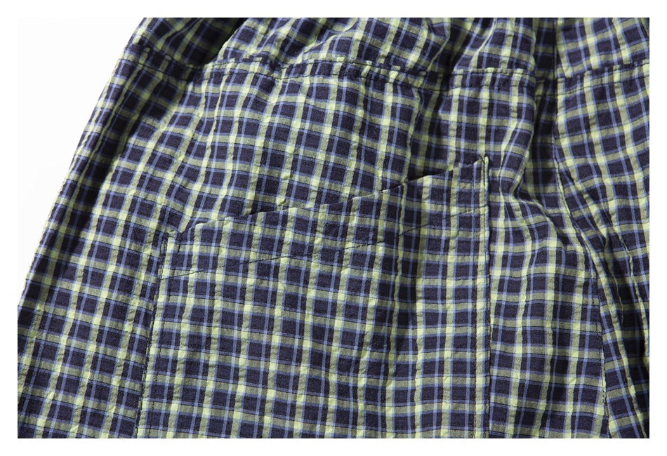 Close-up of a navy plaid garment with pale yellow and light blue checks and a large stitched pocket.