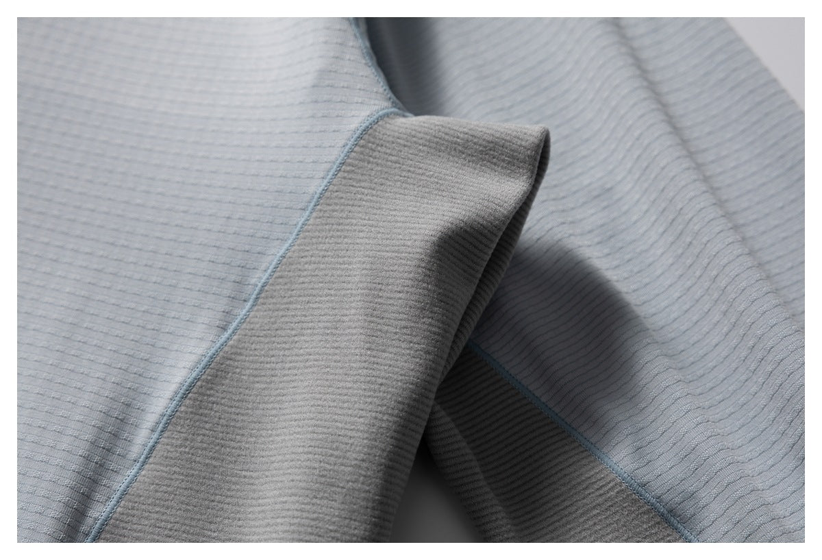 Close-up of a folded sleeve cuff showing the gray-blue textured fabric and seam stitching.