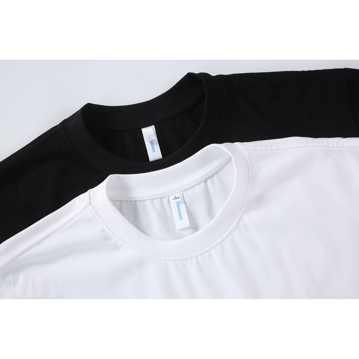 Close-up of black and white crew-neck T-shirts showing their collars and neck labels.