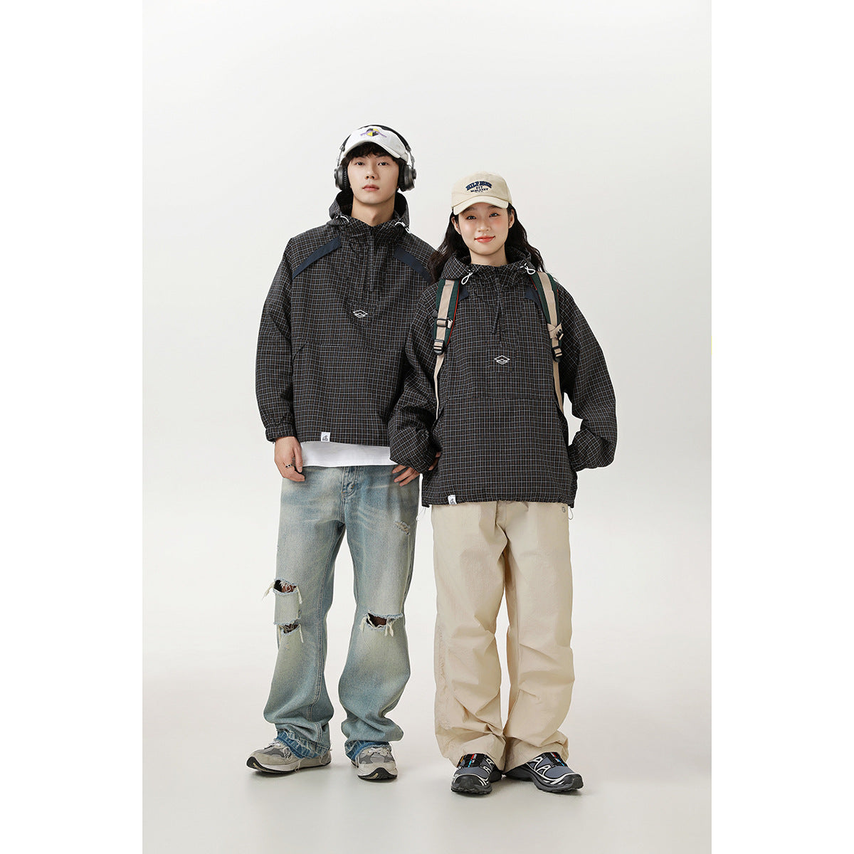 Man and woman model matching black checked hooded pullover jackets with front pockets and drawstrings.