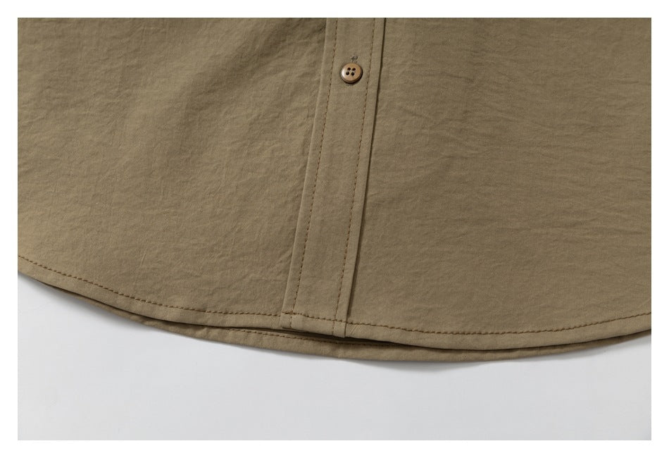 Close-up of the curved bottom hem and button placket of a tan shirt.