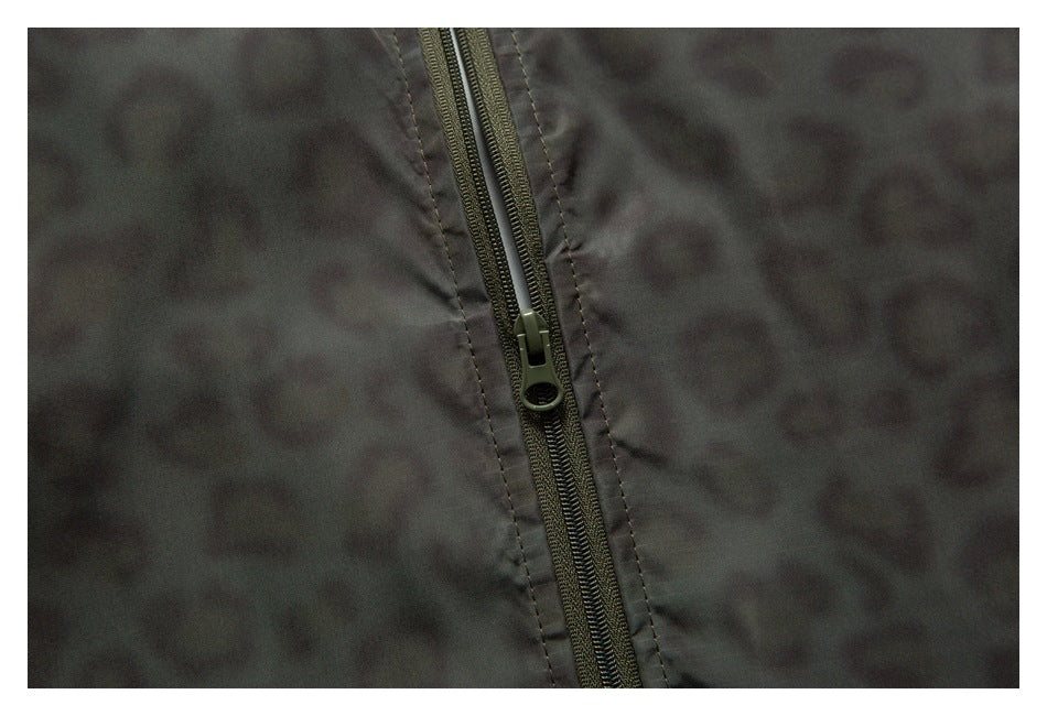 Close-up of a dark olive zipper on the jacket's charcoal leopard-print fabric.