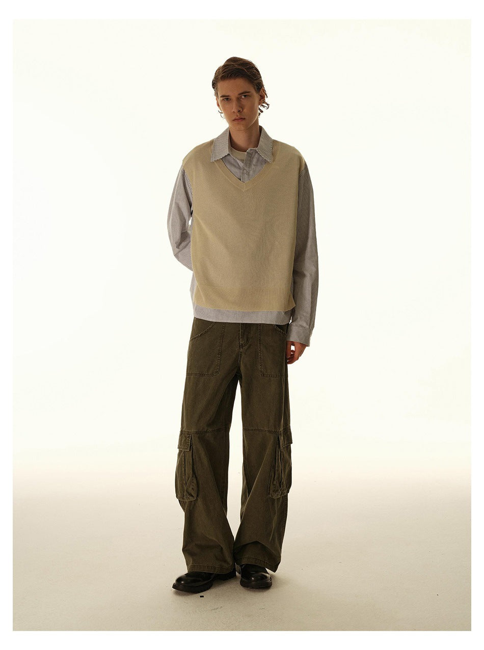 Full-length male model facing forward in a beige V-neck vest, striped shirt, and olive cargo pants.