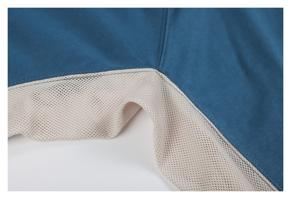 Close-up of a cream mesh panel joined to blue fabric at the sweatshirt's side seam.