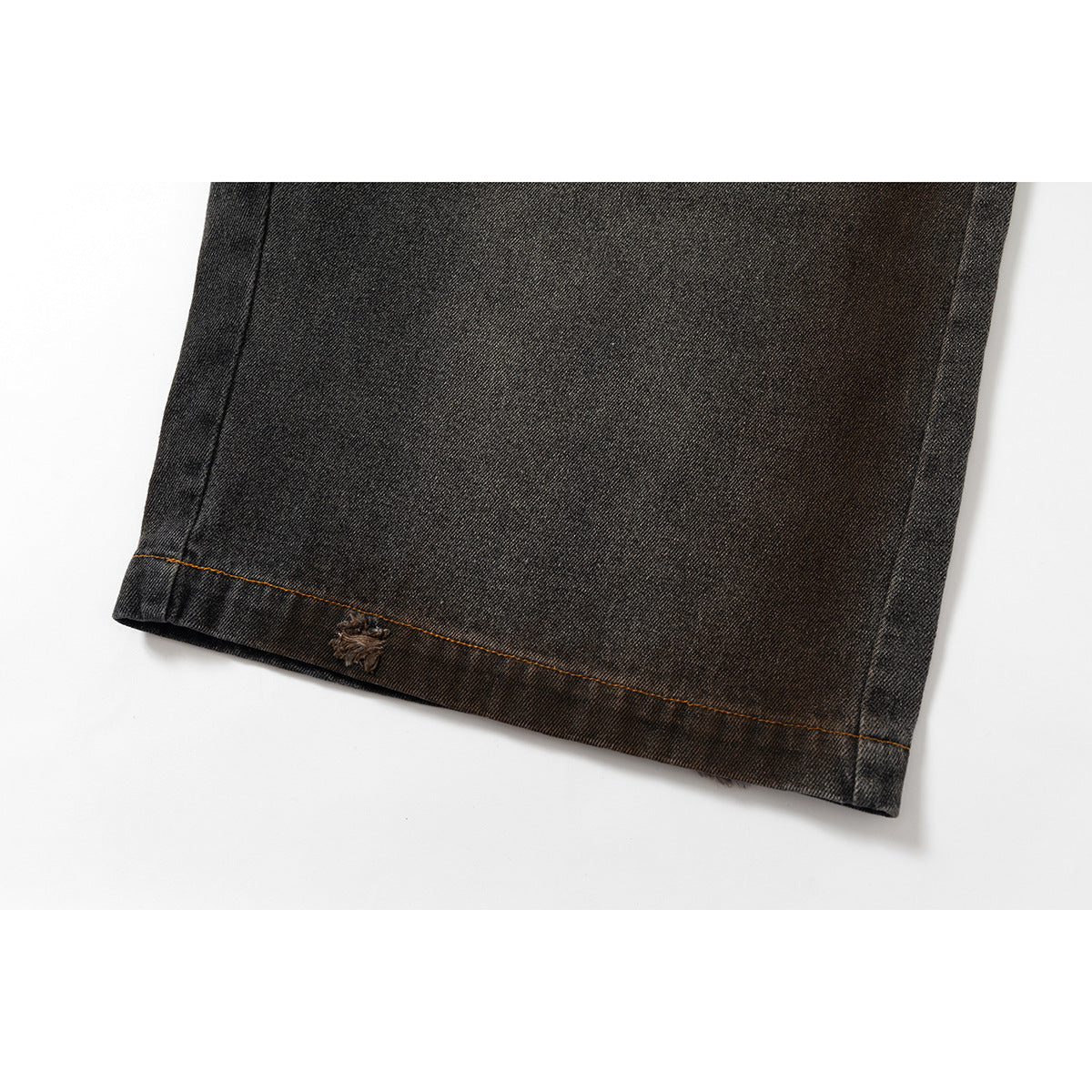 Close-up of a hem on charcoal washed denim shorts, with orange stitching and a small distressed embellishment.