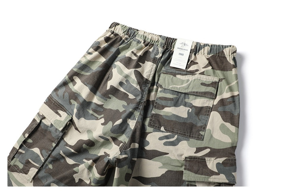 Cropped rear view of flat-laid camouflage cargo trousers with an elastic waist and back and side pockets.