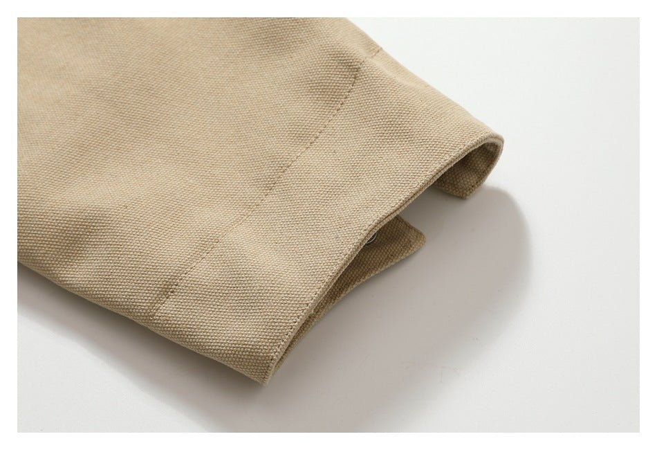 Close-up of a beige garment's folded cuff and stitched seam against a white background.