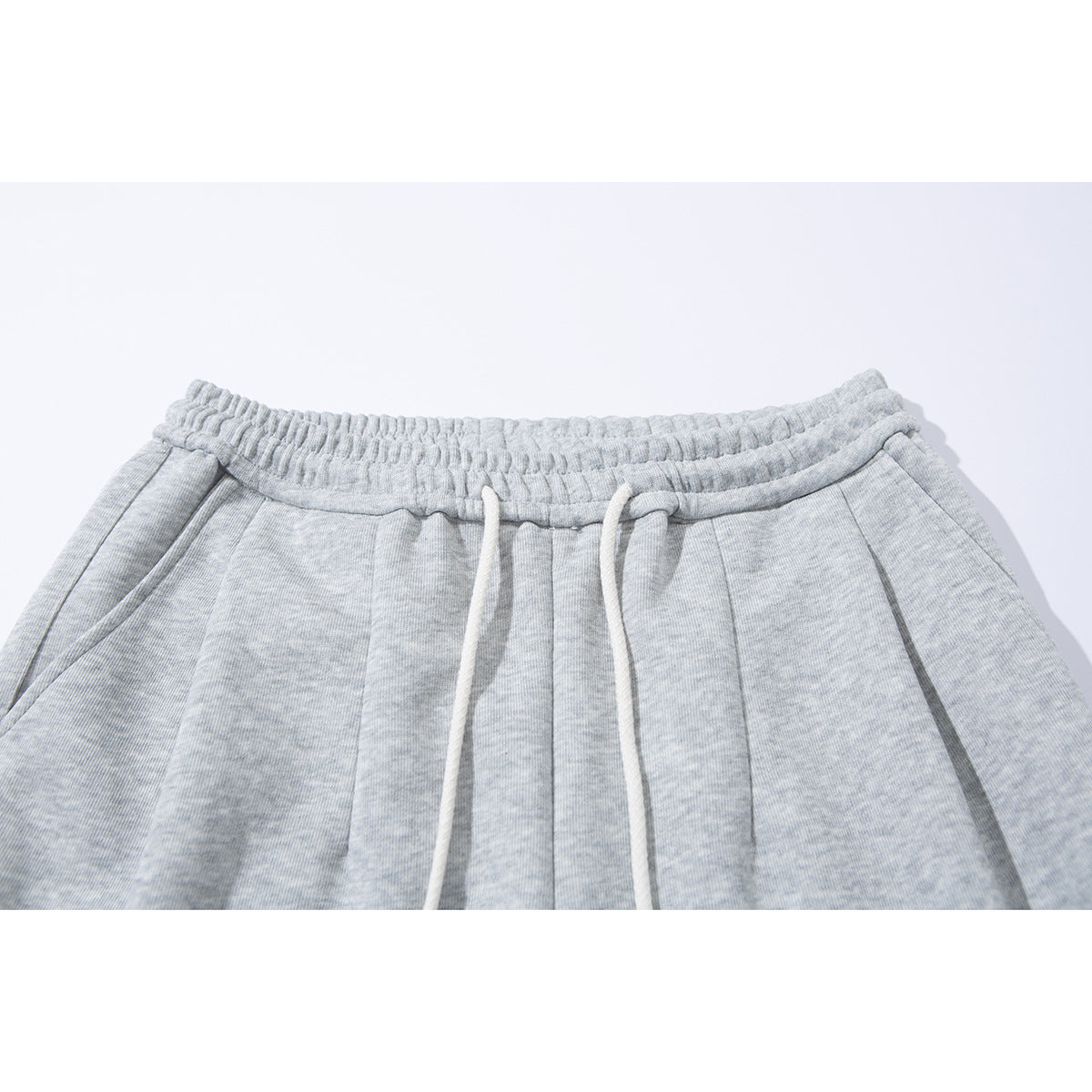 Close-up of light gray heather wide-leg sweatpants with an elastic waistband and white drawstrings.
