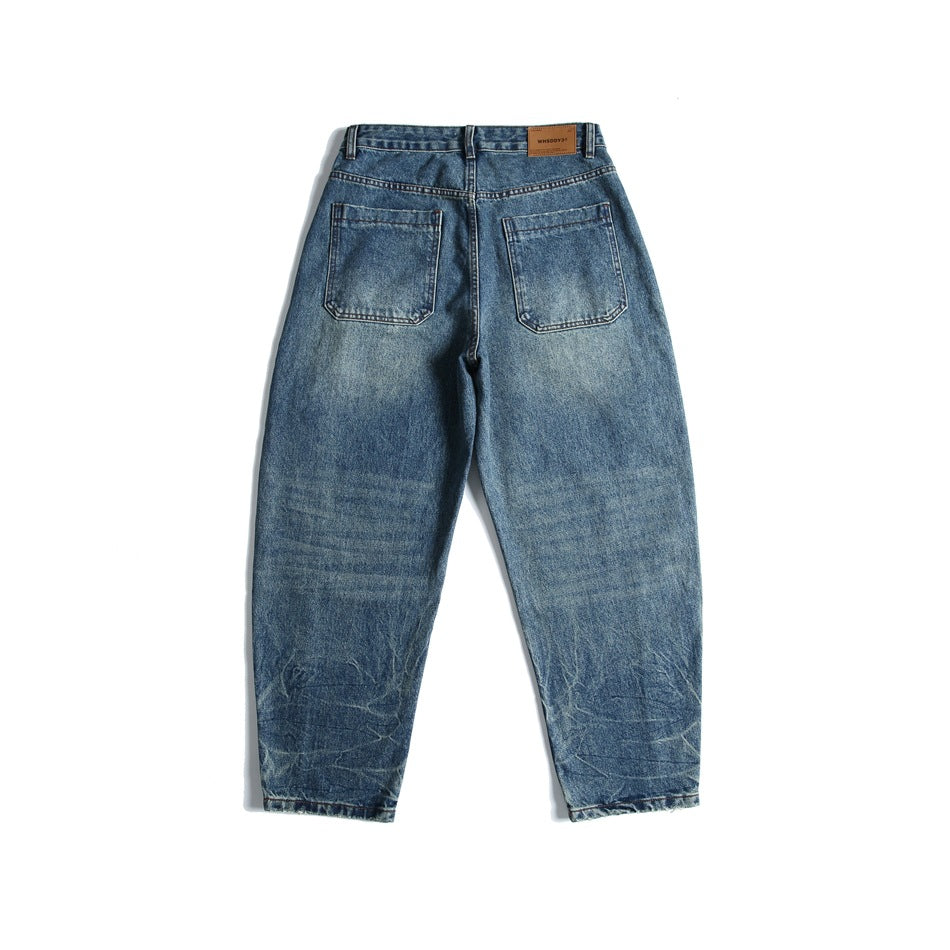 Back view of blue washed denim jeans with two patch pockets and a leather-look waist patch, laid flat on white