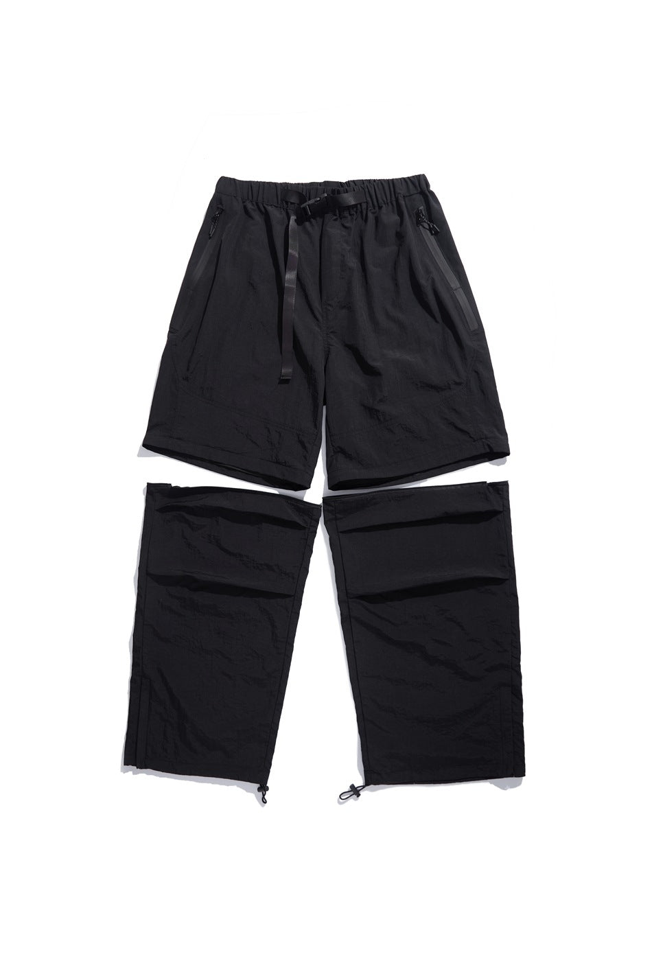 Black convertible pants laid flat with the lower legs detached, showing the elastic waist, belt and zip pockets