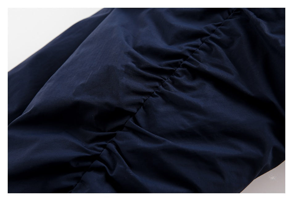 Close-up of gathered stitching in the dark navy fabric of a jacket.
