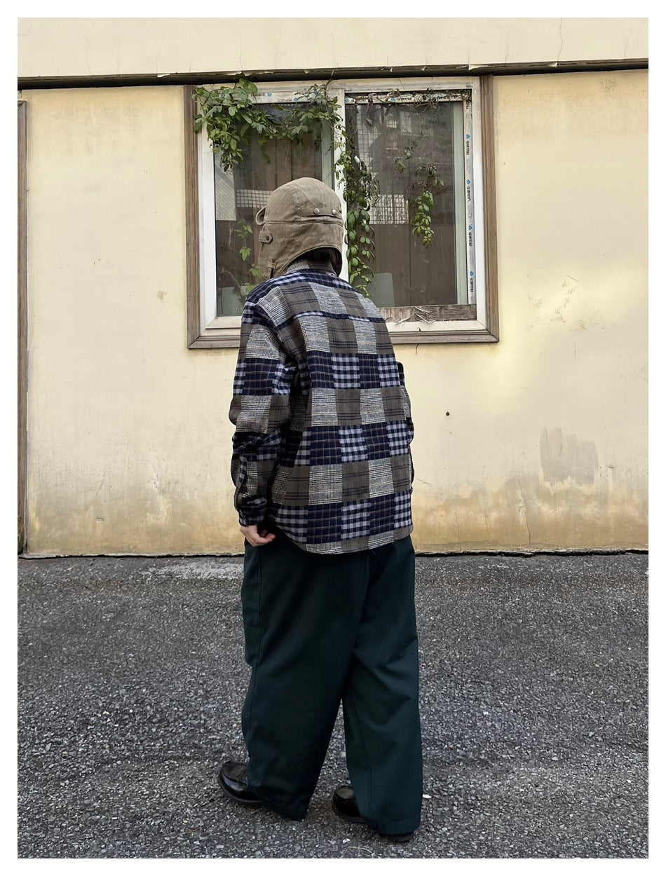 Back view of a person wearing the patchwork plaid shirt with a hat and wide dark green trousers
