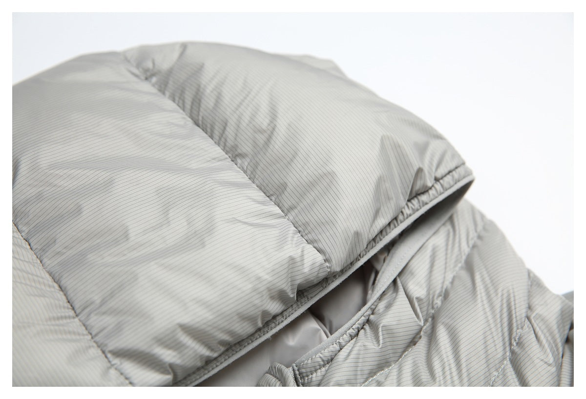 Close-up of a light gray, finely pinstriped quilted jacket with padded panels and a partially open edge.