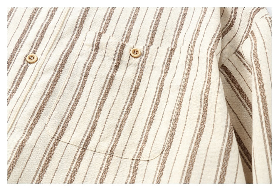 Close-up of a cream striped shirt's chest pocket, buttons, and sleeve.