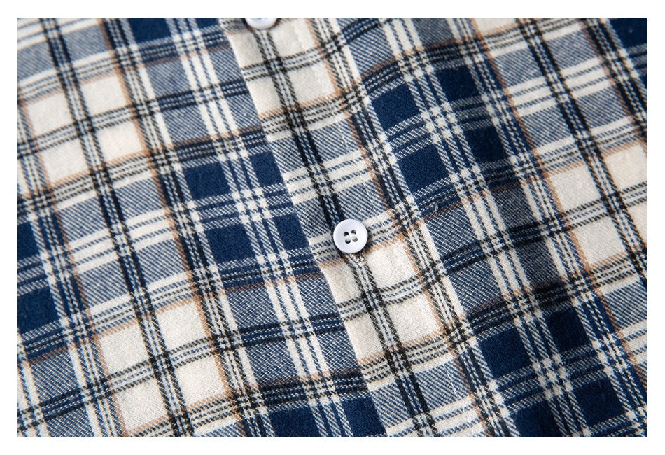 Close-up of a navy, cream, and tan plaid shirt with a white button.