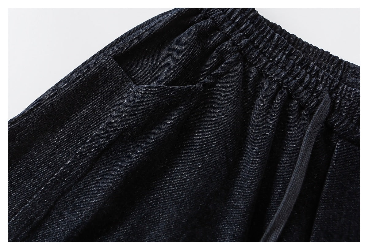 Close-up of black pants showing the gathered elastic waistband, drawstring, and upper fabric.