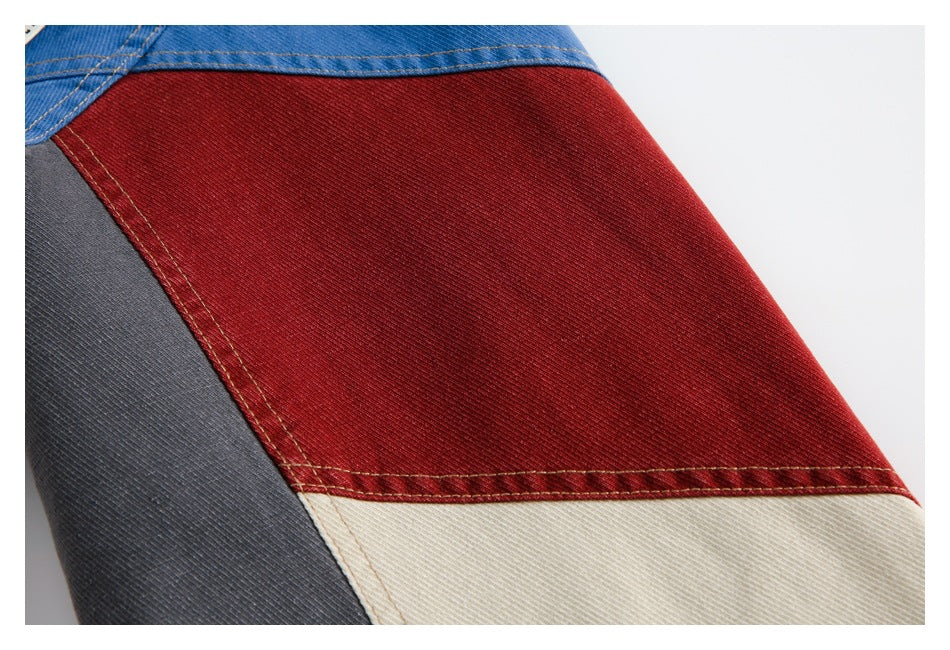 Close-up of a color-block garment with red, cream, blue, and charcoal panels and visible stitching.