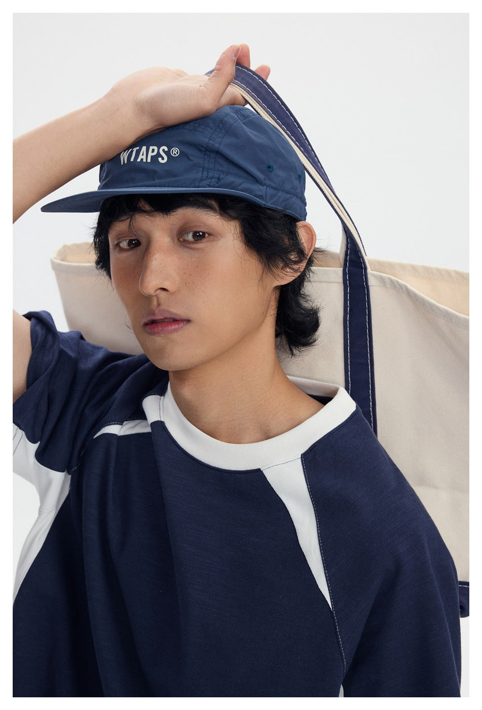 Close-up of a model wearing a navy T-shirt with a white collar and contrasting raglan panels.