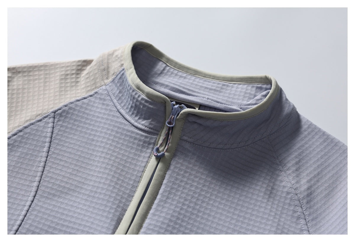 Close-up of the pale gray jacket’s stand collar and front zipper with light trim and a cord zipper pull.