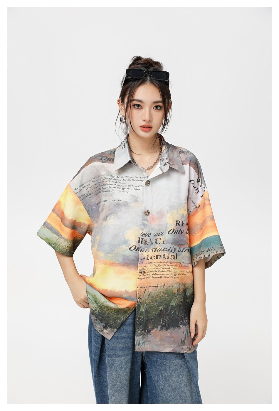 Waist-up front view of a model wearing a collared shirt with a colorful landscape and English text print.