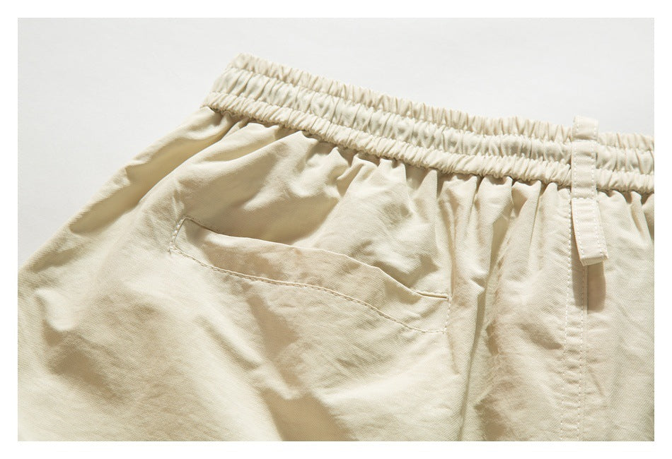 Close-up of a cream-beige trouser waistband, belt loop, and one rear pocket.