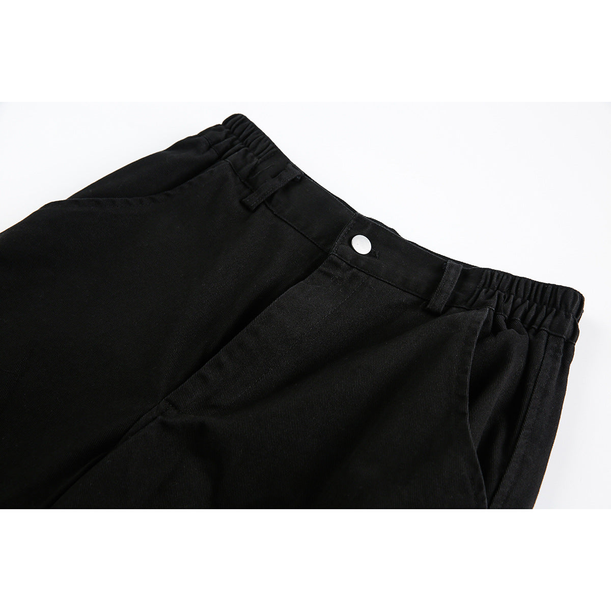 Close-up of black shorts showing the buttoned waistband, belt loops, and front pocket.