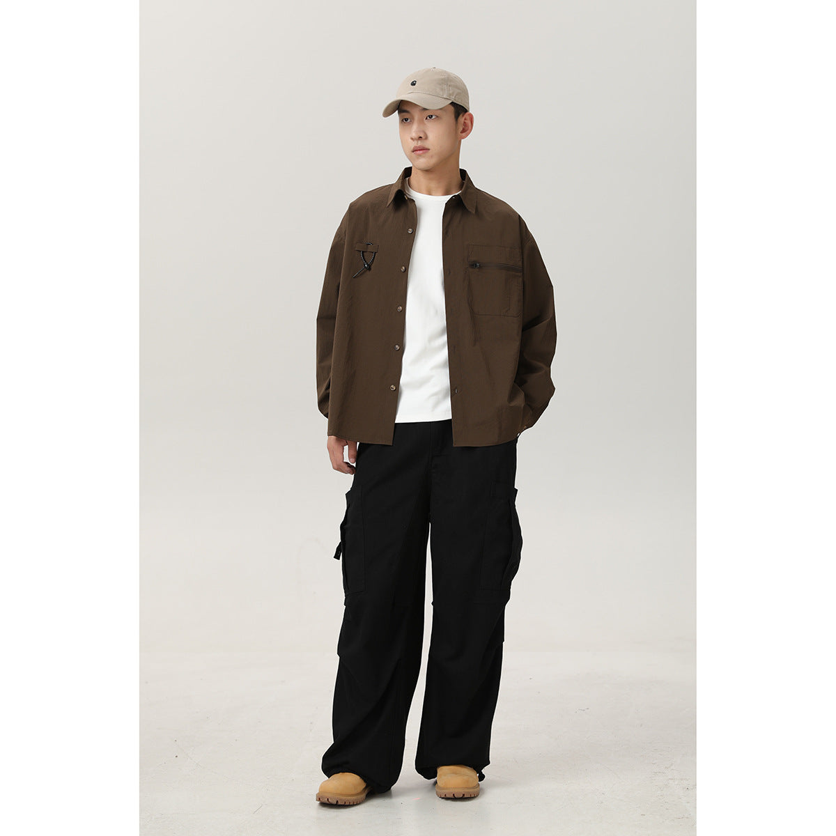 Model wearing a dark brown button-front shirt with chest pockets and black cargo pants, shown full length.
