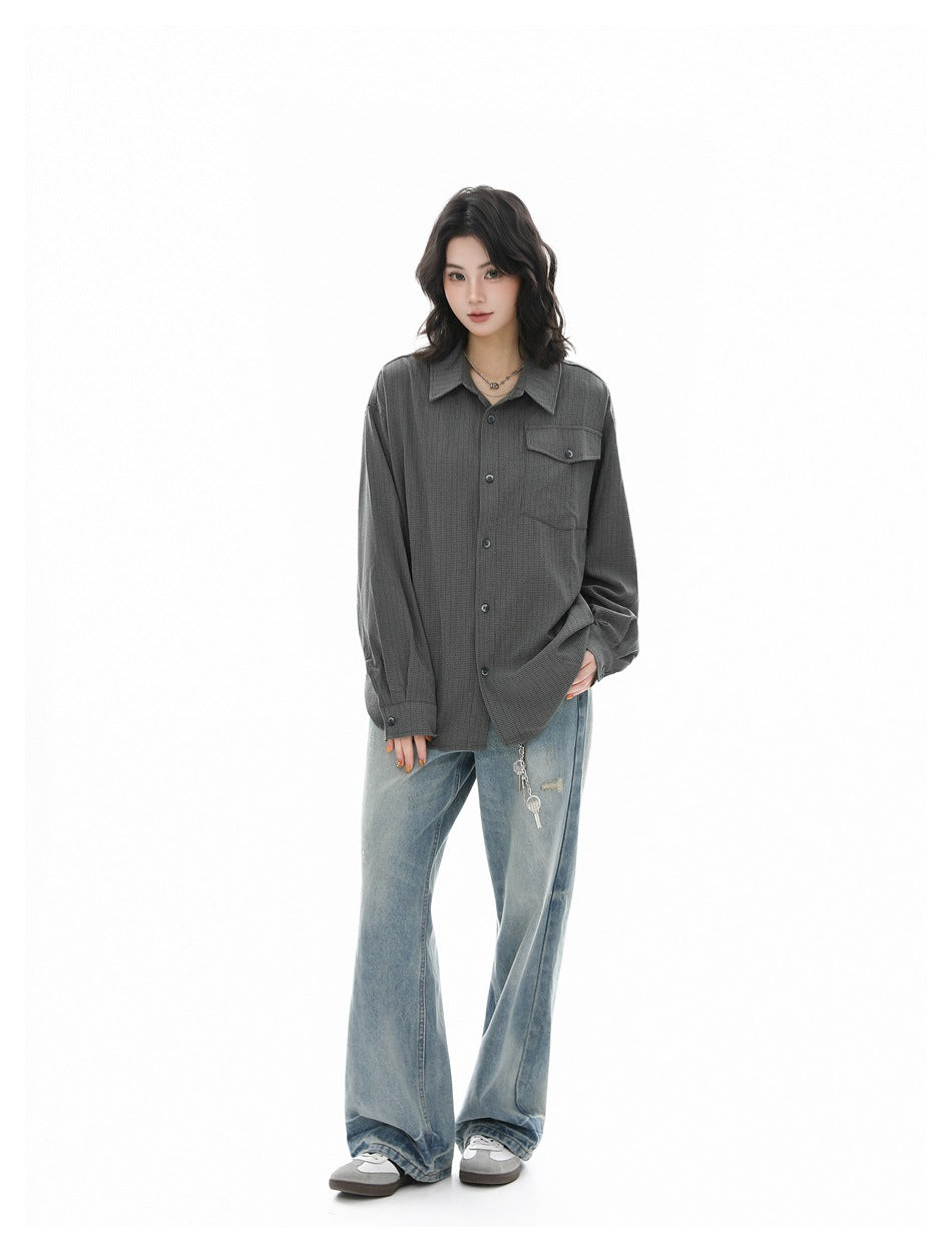 Full-length view of a model wearing an oversized charcoal gray button-up shirt and loose faded blue jeans.