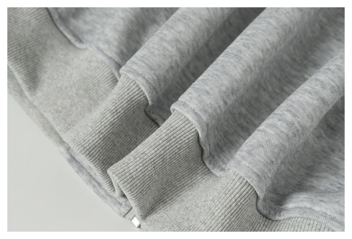 Close-up of a light gray heather sweatshirt with ribbed cuffs and a small visible zipper pull.